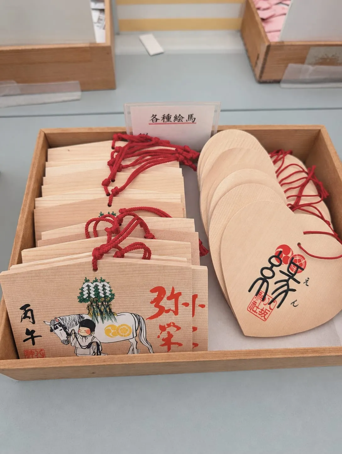 Ema plaques with red cords laid out in a wooden tray at Yasaka Shrine, September 13, 2026