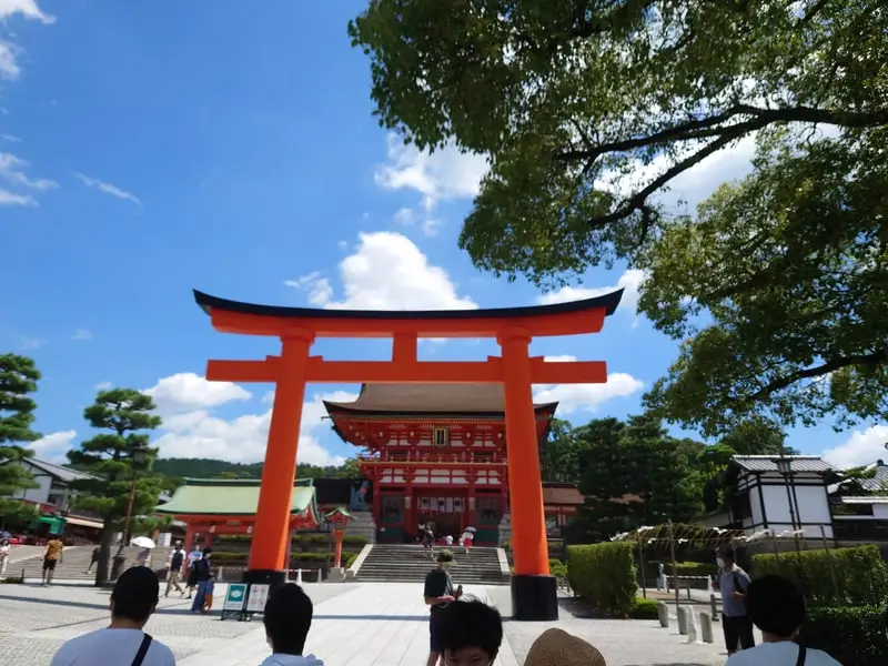 The vermilion gate and main hall of Fushimi Inari Taisha under a summer sky