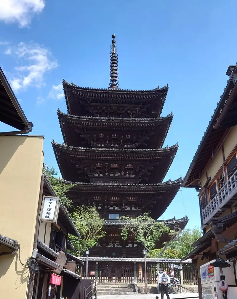 A wooden five-storied pagoda rising above a narrow street in the Higashiyama district of Kyoto