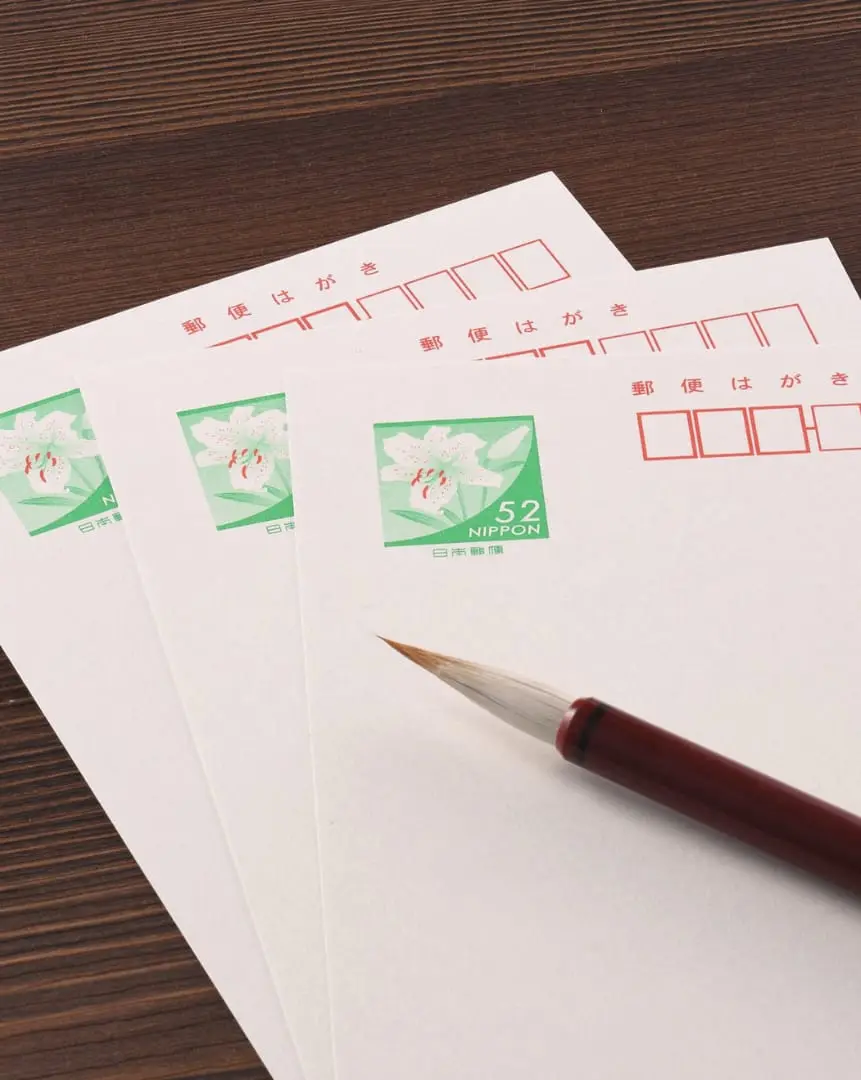 Blank postcards and a writing brush on a wooden desk