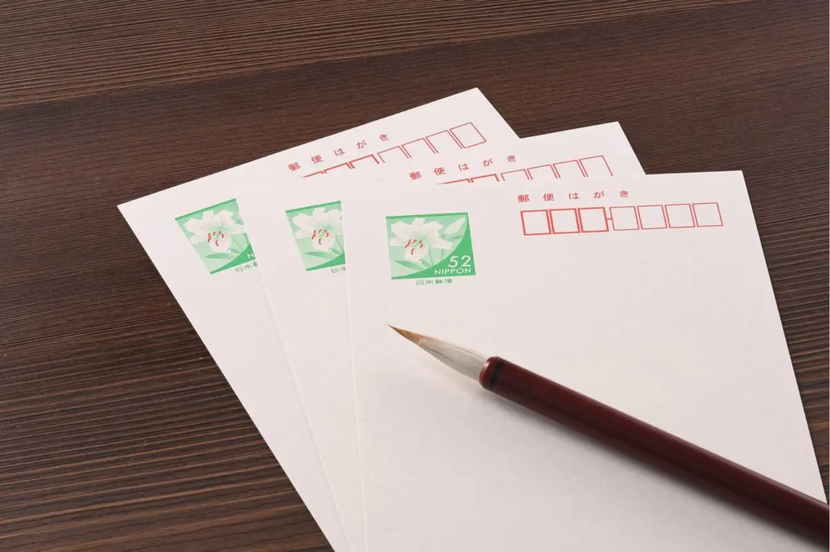 Three blank postcards and a writing brush on a wooden desk