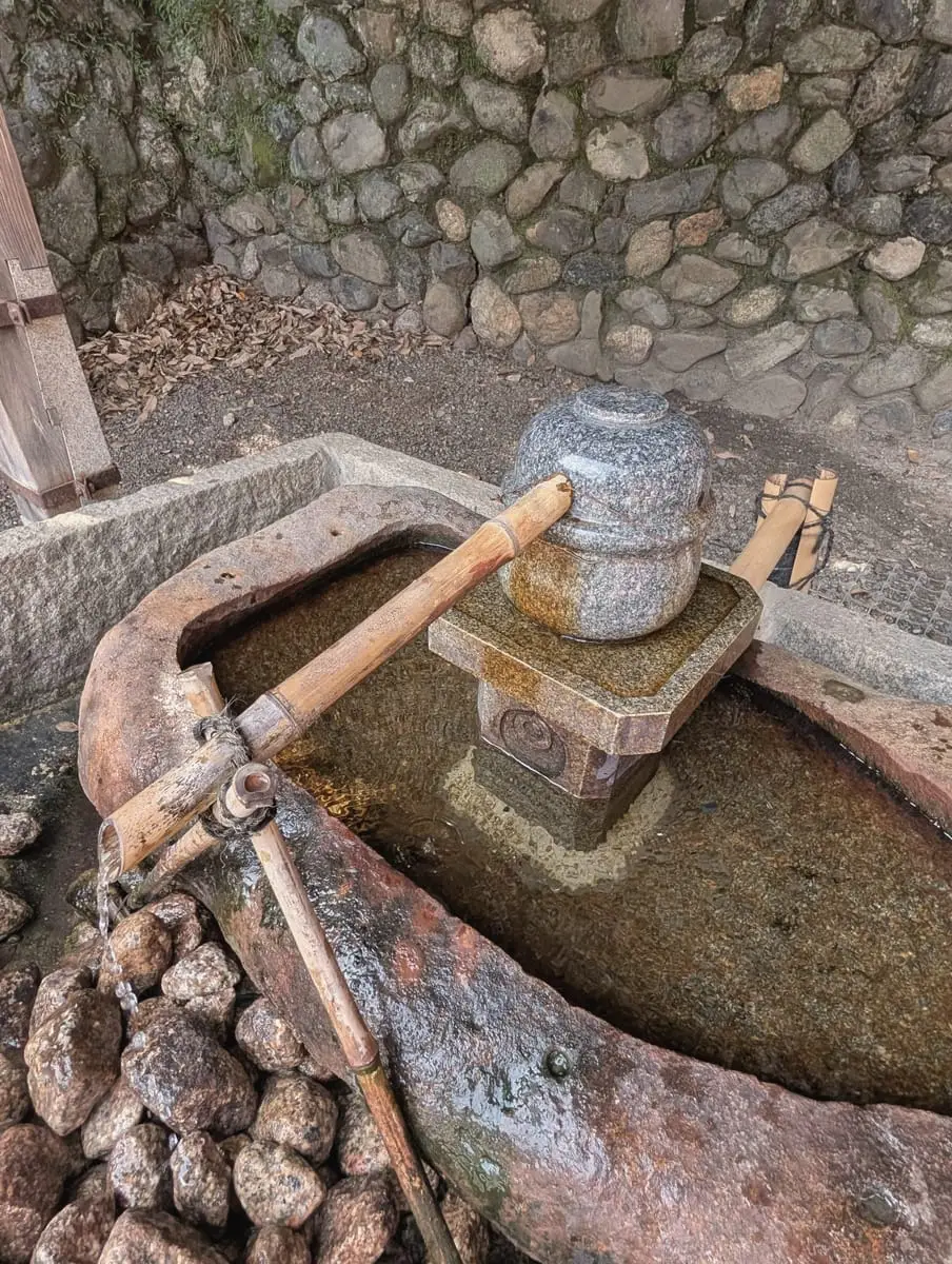 A stone water basin with bamboo ladles for ritual purification
